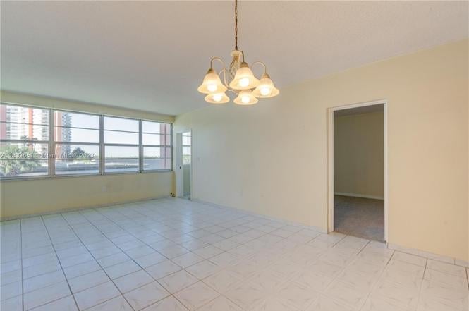 Empty apartment interior with tile flooring, pendant light fixture, and open doorway, with windows overlooking city skyline